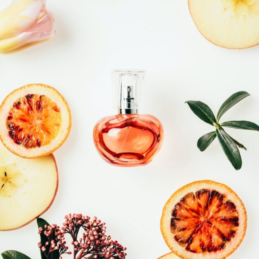 top-view-of-bottle-of-perfume-surrounded-with-fruits-and-flowers-on-white